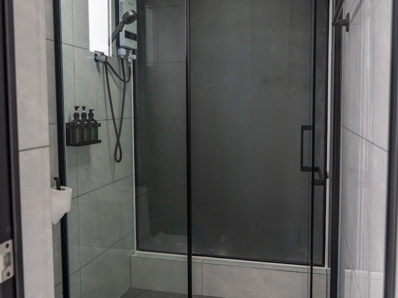 Modern matte-black framed sliding shower door with tinted glass