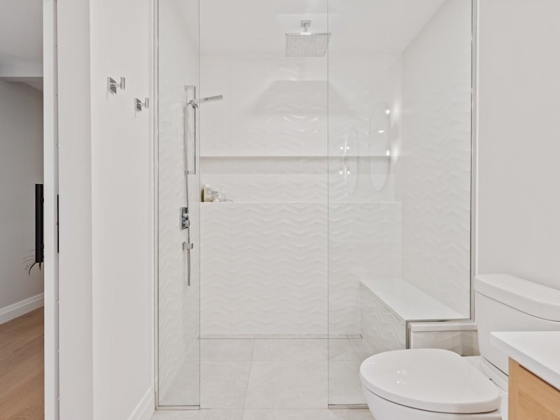 Walk-in shower with frameless glass shield and textured tile